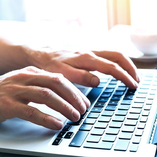 close up of hands typing on a keyboard