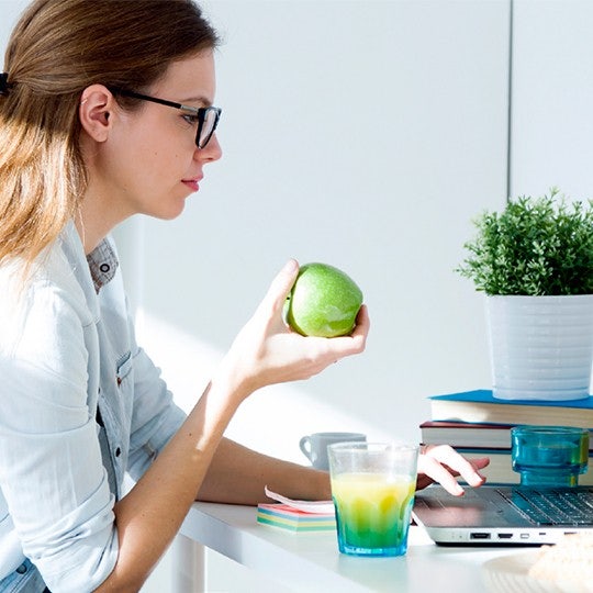 women holding apple and looking at screen