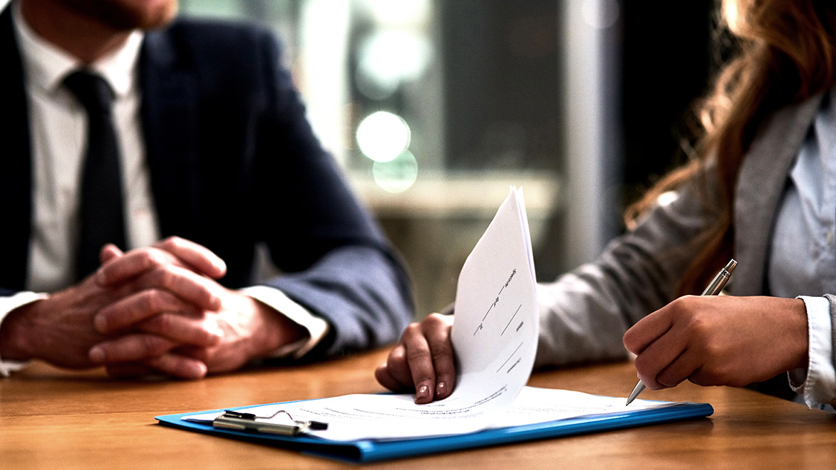 colleagues in a meeting discussing papers on a clipboard