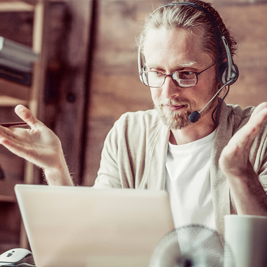 man talking on headphones and looking at computer screen