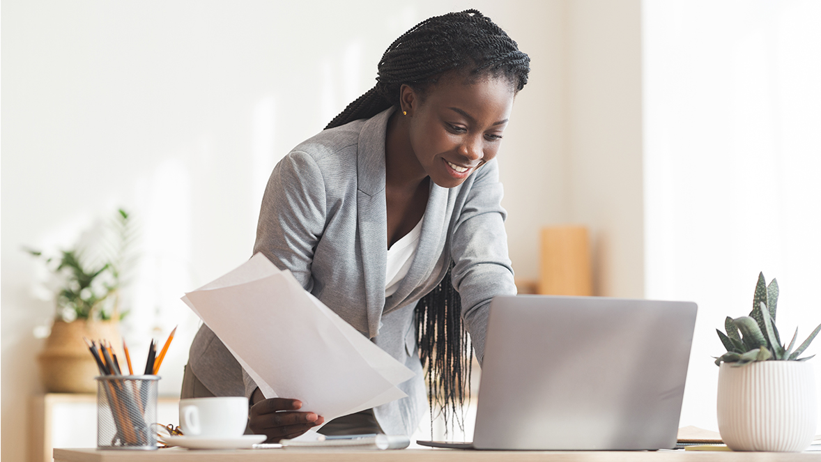 Lady holding paper and looking at laptop