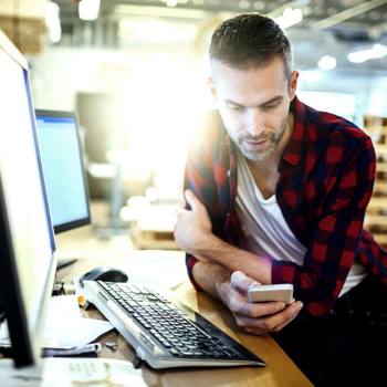 Grow your business towards digital transformation man sitting in front of a laptop checking his phone